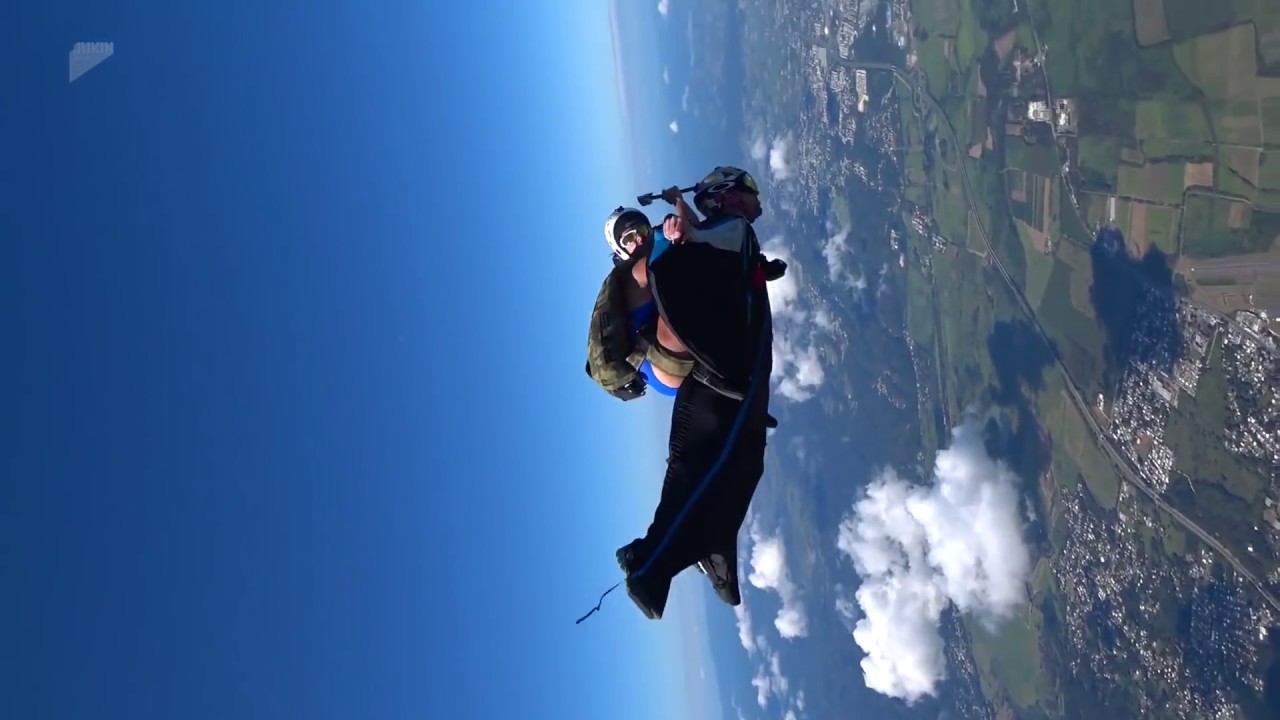 girl in bikini rides a guy in wingsuit